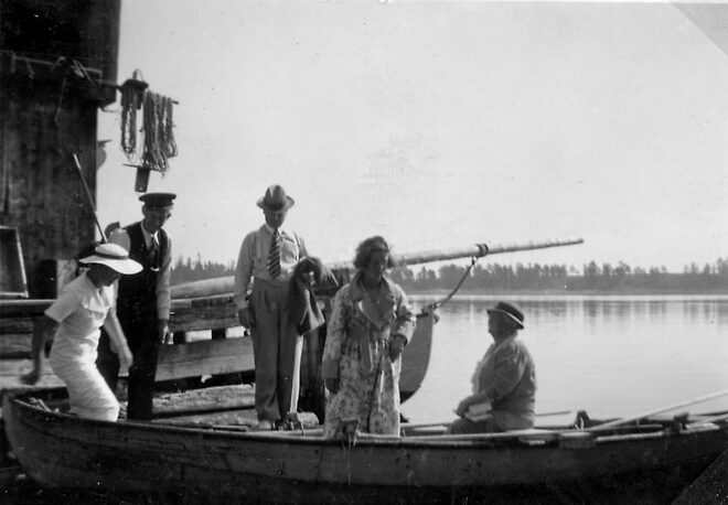 Bilden visar finklädda turister som kliver ner i en träbåt