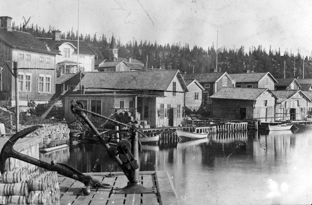 Bilden visar en vy över Ulvöhamn med bostadshus och sjöbodar