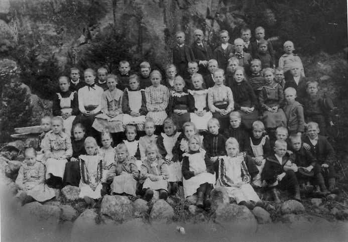 Ett skolfoto med en skolklass med många barn och en lärare.