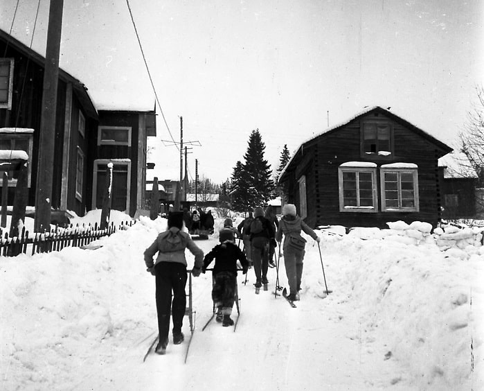 Barn med spark eller på skidor på väg uppför en backe.