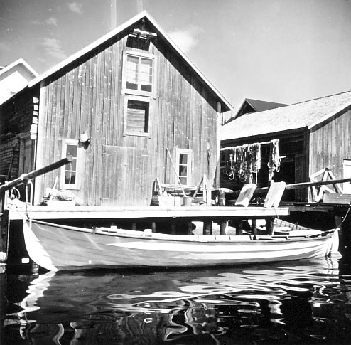 Bilden visar en båt utanför en sjöbod