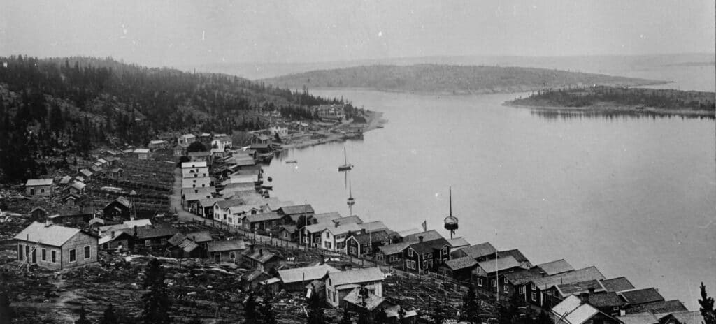 Vy över Ulvöhamn med sjöbodar, båtar och gistvallar