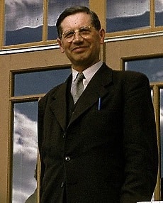 Bilden föreställer en man med glasögon klädd i kostym